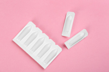 Suppositories on pink background, flat lay. Hemorrhoid treatment