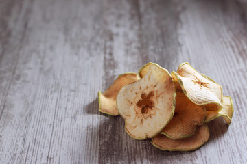 Organic apple chips or dried apples on a wooden surface. Healthy snacks. Place for text. Copy space.