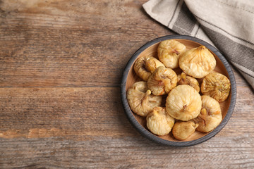 Tasty dried figs in plate on wooden table, top view. Space for text