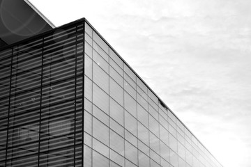 Obraz premium Sun rays light effects on urban buildings in sunset. Modern office building detail, glass surface with sunlight. Business background. Black and white.