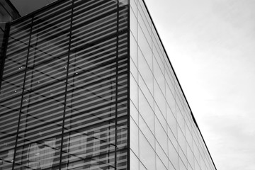 Fototapeta na wymiar Sun rays light effects on urban buildings in sunset. Modern office building detail, glass surface with sunlight. Business background. Black and white.