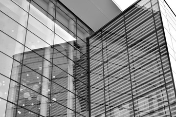 Fototapeta premium Sun rays light effects on urban buildings in sunset. Modern office building detail, glass surface with sunlight. Business background. Black and white.