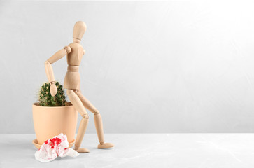 Wooden human figure, cactus and sheet of toilet paper with blood on table, space for text. Hemorrhoid problems