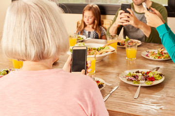 Family having dinner with smartphone and mobile phone