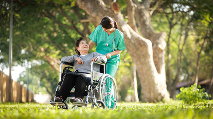 Asian senior woman sitting on the wheelchair  with woman in doctor uniform in the park hospital