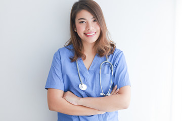 Asian woman in blue doctor uniform using telephone on white background