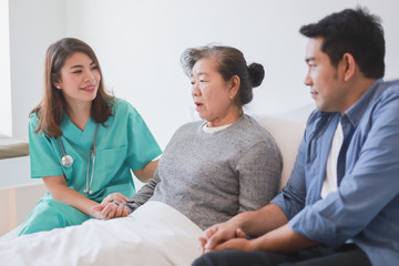 Asian Senior old woman on the bed with doctor and her son in hospital