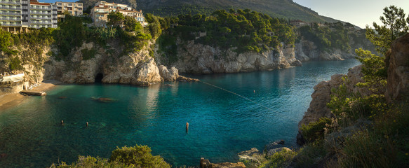 Panorama of sea lagoon between rocky cliffs with trees and buildings at the top