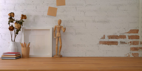 Cropped shot of vintage workplace with mock up frame and office supplies on wooden table and brick...