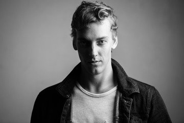 Face of young handsome man with curly hair in black and white