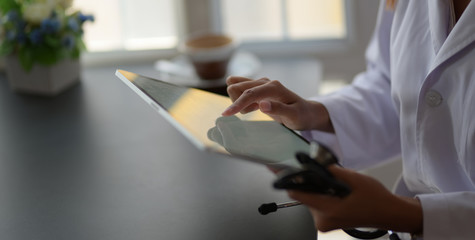 Young female doctor analysing medical charts with tablet