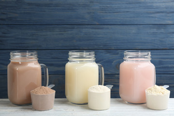 Protein shakes and powder on white wooden table