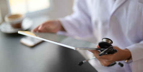 Cropped shot of young female doctor reading medical charts with tablet