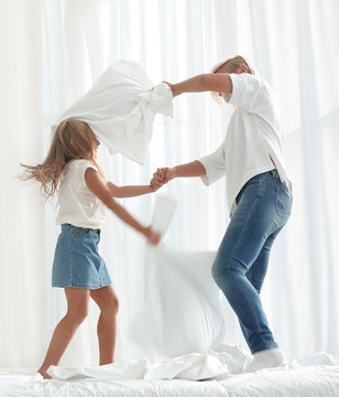 Close Up. Mom And Daughter Have A Pillow Fight On The Bed