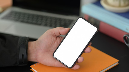 Close-up view of young businessman using blank screen smartphone while working