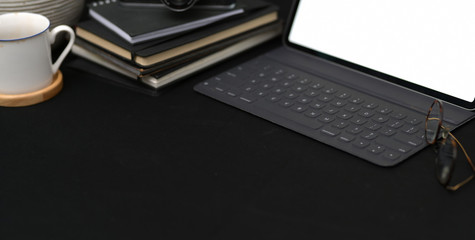 Cropped shot of dark trendy workplace with tablet and office supplies with copy space