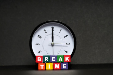 Break Time Concept. Clock with colorful wooden block on black background