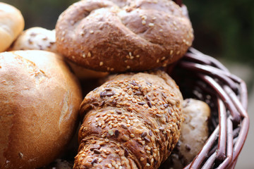 Tasty freshly baked butter kaiser roll with linseed and sunflower seeds. Pastrys in basket. Blurred background. Concept of fresh pastry.