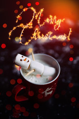 Cute little snowman made from marshmallows bathing in a mug with hot chocolate