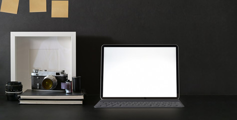 Cropped shot of trendy photographer workplace with blank screen tablet and camera