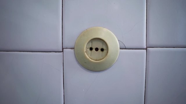 Old socket on the wall. Short circuit. Old power grid. Voltage drop in the room. The light is blinking. Danger. Lighting turn on and off. Power source. House of Horror.