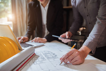 Businessman working as a team discussing data working and tablet, laptop with on on architectural project at construction site at desk in office.