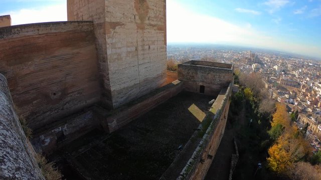 Tilt up view of the Torre de la Vela (Candle tower) in the Alcazaba of Alhambra from the outside. Views of Granada and the Cathedral in the background. Andalusia, Spain.