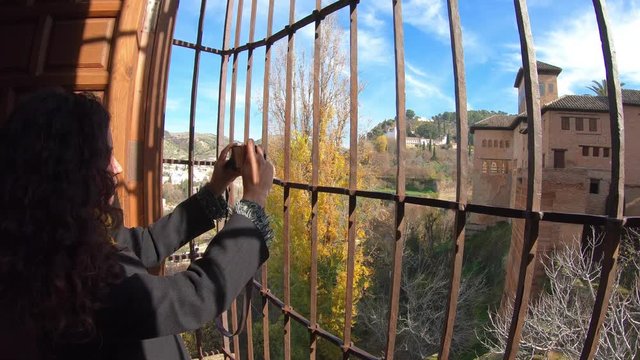 Tourist taking a photo to the exterior of Palacios Nazar&iacute;es (Nasrid Palaces) of la Alhambra through a window. Granada, Andalusia, Spain.