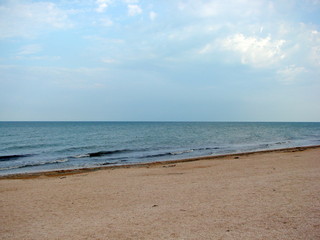 Panorama of the coast of the Azov Sea on a background of cloudy evening sky at sunset.
