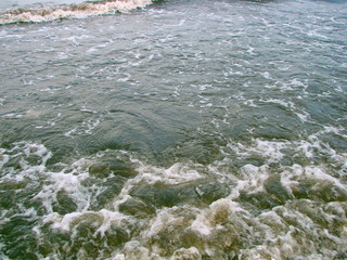 Natural picture of coastal sea waves foaming on a sandy beach.