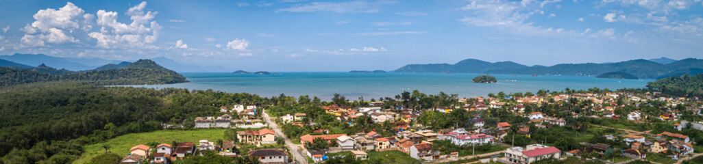 Fototapeta na wymiar Aerial view panorama of Jabaquara, Paraty with buildings, Bay Carioca, mountains, islands and blue sky with clouds, Brazil