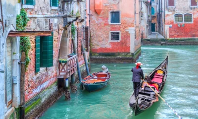Wall murals Venetian gondolier punting gondola through green canal waters of Venice Italy