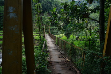 a suspension bridge still made of wood and an iron stand was used to cross the river connecting the two villages