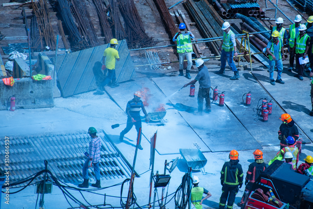 Wall mural Construction workers wearing helmets at a construction site learning fire fighting skills