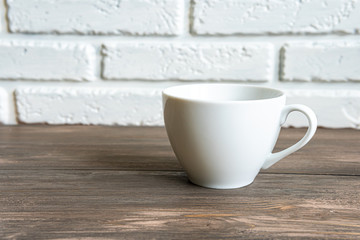 Cup on the table in front of a white brick wall