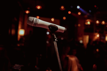 Obraz premium Professional stage microphone in bright spot light beam over dark background