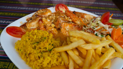 Fried breaded shrimp with rice and vegetables on a white plate