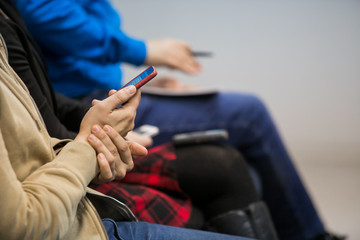 Close-up shot of unrecognizable journalists sitting in row with notepad sin hands while participating in press conference