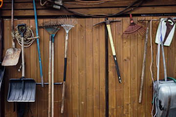 shovels rakes hammers hanging on wooden wall