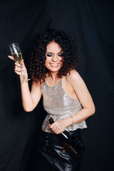 Funny beautiful woman dancing with glass of champagne and smiling. Girl is happy about the New Year