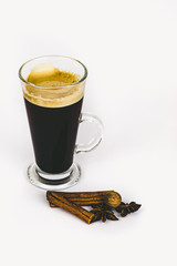 GLASS CUP OF COFFEE WITH CINNAMON ON WHITE BACKGROUND