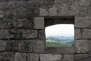 Window on an ancient stone wall with a view of a mountain panorama