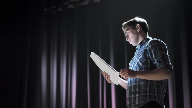 Stand up comedian on stage. Young man talks joke into microphone or sings songs.