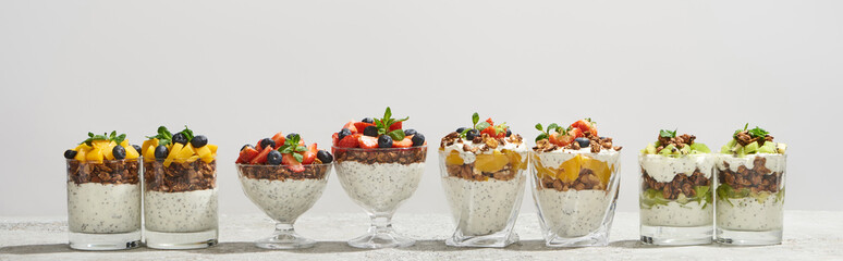 delicious granola in glasses with fruits and berries isolated on white, panoramic shot