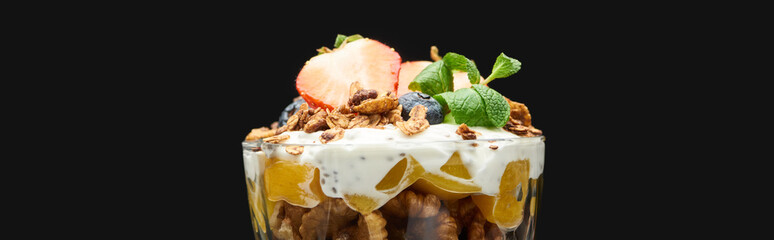 fresh granola with canned peach, berries, walnuts and chia seeds isolated on black, panoramic shot