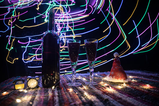 Red wine in crystal glass with bottle on colorful carpet with creative New Year artwork decorations. Copy space