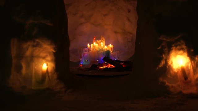 Christmas installation inside of snow house with colorful icy plafonds and burning candles at night