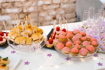 Festive buffet, canapes and sweet cupcakes on the table