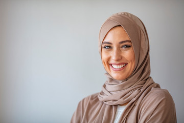 Woman in traditional Muslim clothing, smiling. Woman headshot looking at camera and wearing a hijab. Arabian woman with happy smile. Strict formal outfit and elegant appearance. Islamic fashion. - obrazy, fototapety, plakaty