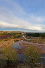 The Lunan River gently winding itself through the hills and farmland behind Lunan Bay on the east coast of Scotland in December.